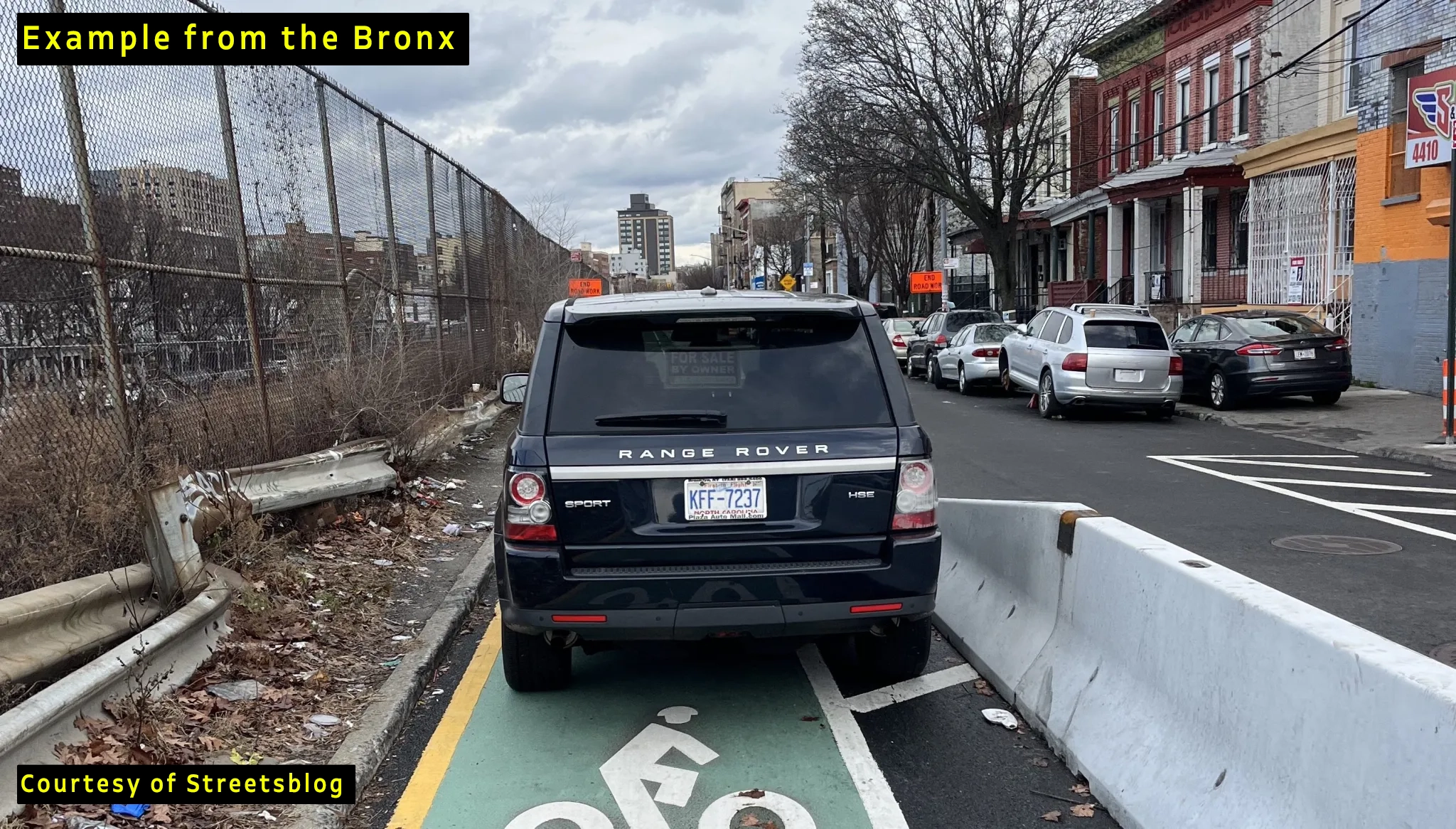 image of car blocking bike lane protected by concrete barriers.
